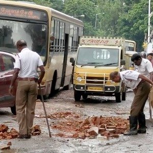 Policemen fill potholes with bricks in a rain lashed Chennai