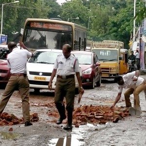 Policemen fill potholes with bricks in a rain lashed Chennai