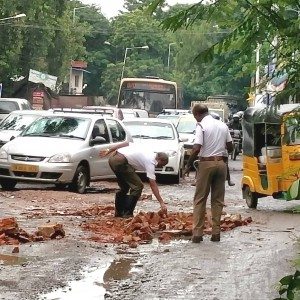 Policemen fill potholes with bricks in a rain lashed Chennai