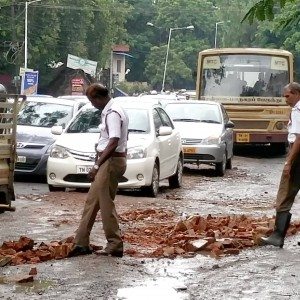 Policemen fill potholes with bricks in a rain lashed Chennai